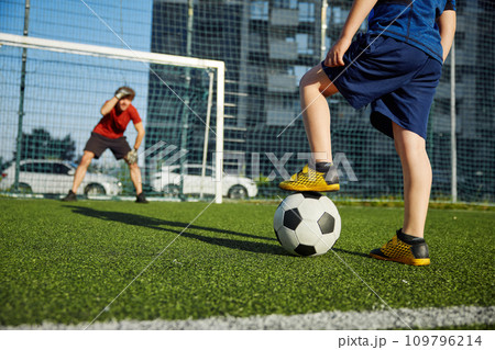 Father goal keeper and schoolboy son forward training football at stadium Father goal keeper and schoolboy son forward training football at stadium 109796214