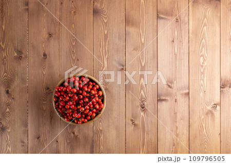 red dog-rose rosehip fruits in a wooden bowl on wooden table red dog-rose rosehip fruits in a wooden bowl on wooden table 109796505