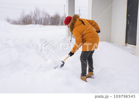 Man removing snow and ice from the sidewalk in front of house. Winter season Man removing snow and ice from the sidewalk in front of house. Winter season 109796545