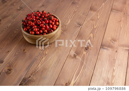 red dog-rose rosehip fruits in a wooden bowl on wooden table red dog-rose rosehip fruits in a wooden bowl on wooden table 109796886
