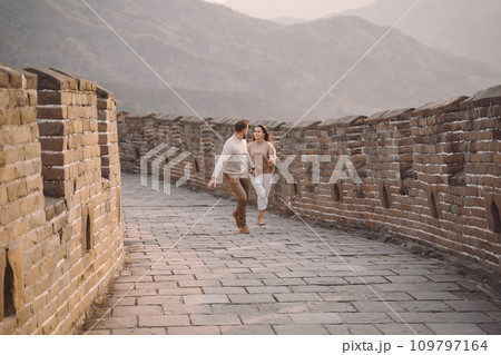 young couple running and twirling at the Great Wall of China. Newly married couple on their honeymoon to the Great Wall of China near Beijing China. 109797164