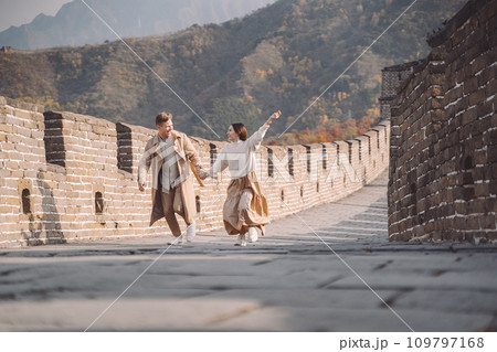 beautiful young couple running and jumping at the Great Wall of China. Newly married couple on their honemoon to Great Wall near Beijing China. Stylish couple exploring one of the wonders of the world beautiful young couple running and jumping at the Great Wall of China. Newly married couple on their honemoon to Great Wall near Beijing China. Stylish couple exploring one of the wonders of the world 109797168