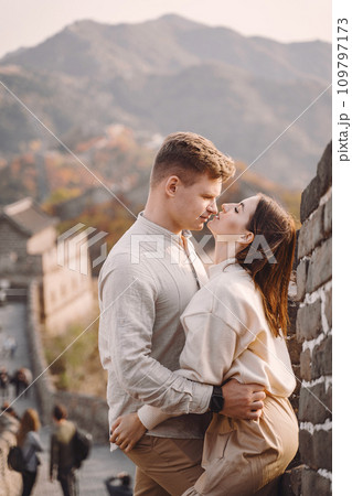 beautiful young couple hugging at the Great Wall of China. Newly married couple on their honemoon to Great Wall near Beijing China. Stylish couple exploring one of the wonders of the world. beautiful young couple hugging at the Great Wall of China. Newly married couple on their honemoon to Great Wall near Beijing China. Stylish couple exploring one of the wonders of the world. 109797173