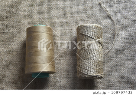Skeins of thread on burlap. Yellow threads on coarse cloth. Skeins of thread on burlap. Yellow threads on coarse cloth. 109797432