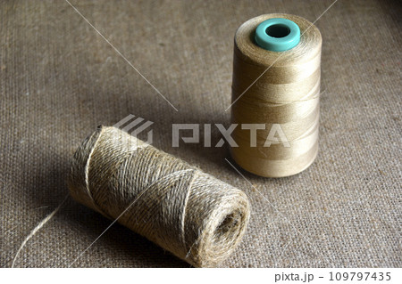 Skeins of thread on burlap. Yellow threads on coarse cloth. Skeins of thread on burlap. Yellow threads on coarse cloth. 109797435