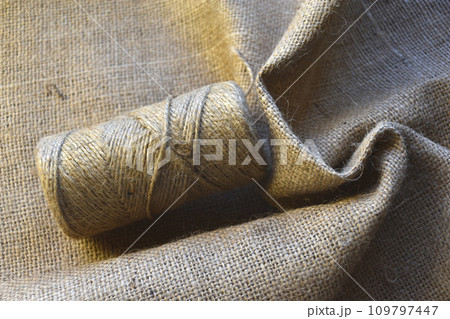 Skeins of thread on crumpled burlap. Yellow threads on coarse cloth. The material for the bags. Skeins of thread on crumpled burlap. Yellow threads on coarse cloth. The material for the bags. 109797447