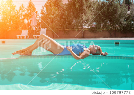 Bikini-clad woman enjoys poolside relaxation. Poolside ambiance. Capturing woman's relaxed time near pool. Bikini-clad woman enjoys poolside relaxation. Poolside ambiance. Capturing woman's relaxed time near pool. 109797778