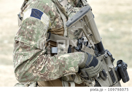 Soldier with assault rifle and flag of Europe on military uniform. Collage. Soldier with assault rifle and flag of Europe on military uniform. Collage. 109798075