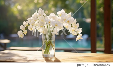 clear clear vase filled with white orchids and water on wooden table 109800825
