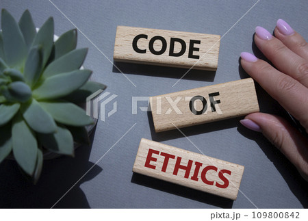 Code of ethics symbol. Concept words Code of ethics on wooden blocks. Beautiful grey background with succulent plant. Businessman hand. Business and Code of ethics concept. Copy space. 109800842