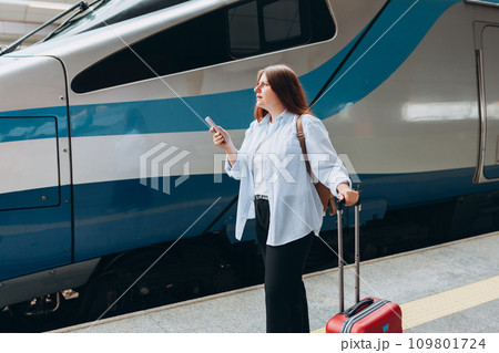 Young worried woman traveler with small backpack on the railway station, 30s redhead women waiting for train. Tourism, solo vacation 109801724
