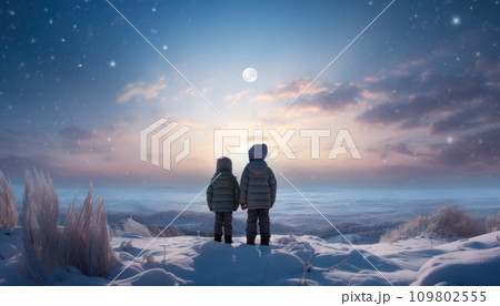 two young boys stand in the snow overlooking a white moon 109802555