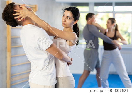 Young girl practicing self-defense techniques in pairs with guy 109807621