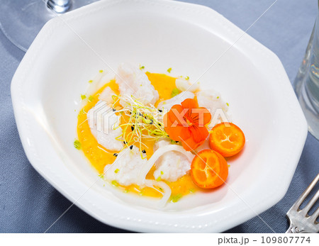 Seafood ceviche from horse-mackerel with spicy avocado sauce, greens and cumquat 109807774