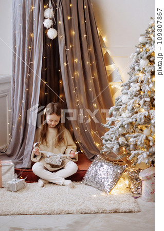 Little girl opening a Christmas gift at home. Little girl opening a Christmas gift at home. 109807867