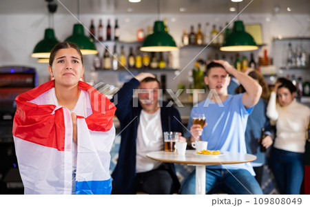 Sad girl with friends upset by the loss of her favorite team of Netherlands Sad girl with friends upset by the loss of her favorite team of Netherlands 109808049
