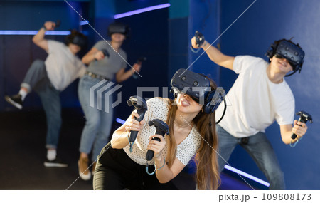 Excited young woman in VR goggles having fun in virtual reality room 109808173