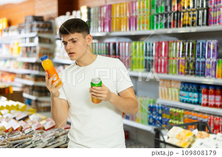 Young guy choosing colored drinks in drinks section of supermarket 109808179