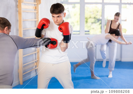 Young guy training boxing with partner during sports classes 109808208