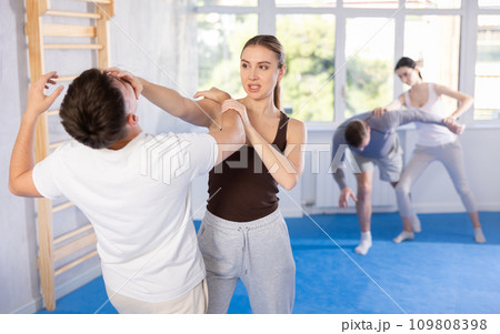Young girl practicing self-defense techniques in pairs with guy 109808398