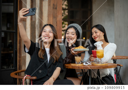 Group of attractive Asian female friends are taking selfies while hanging out at a cafe together. Group of attractive Asian female friends are taking selfies while hanging out at a cafe together. 109809915