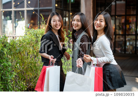 Group of beautiful Asian female friends with their shopping bags, enjoying shopping in the city. 109810035