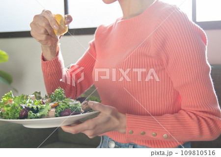 サラダにレモンを絞る女性 109810516