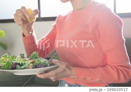 サラダにレモンを絞る女性 109810517
