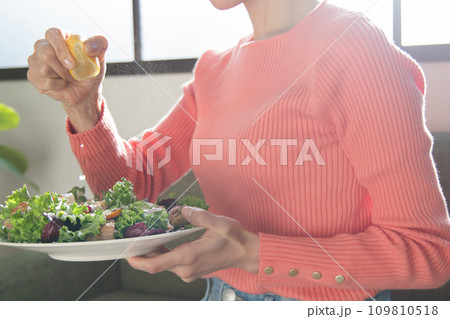 サラダにレモンを絞る女性 109810518