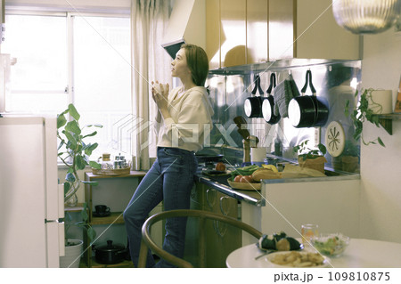 キッチンでコーヒーカップを持つ若い女性 キッチンでコーヒーカップを持つ若い女性 109810875