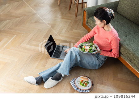 自宅で食事しながらパソコンを操作する女性 自宅で食事しながらパソコンを操作する女性 109816244