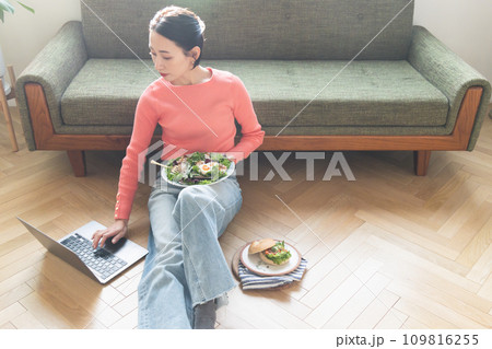 自宅で食事しながらパソコンを操作する女性 109816255