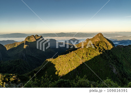 View from the top of Doi Luang Chiang Dao during a morning sunrise with trees and shrubs in the foreground and beautiful mountain ranges in background 109816391