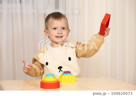A two-year-old boy plays with wooden toys to develop logic and motor skills A two-year-old boy plays with wooden toys to develop logic and motor skills 109820073