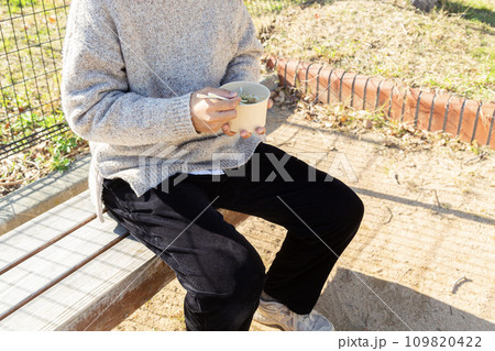ベンチで昼食をとる人 109820422