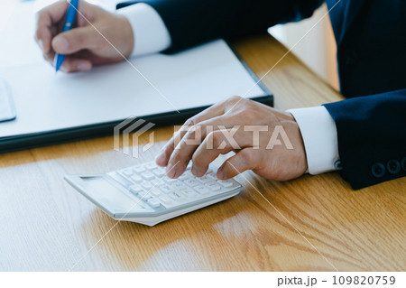 電卓を叩くスーツ姿の男性の手元 109820759