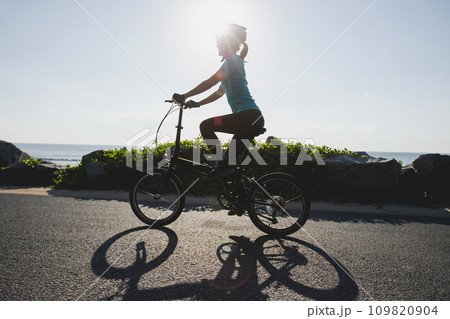 Riding folding bike on sunrise seaside road Riding folding bike on sunrise seaside road 109820904
