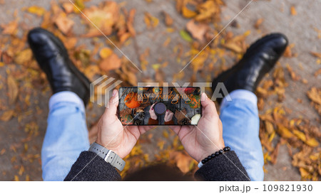 Man holding smartphone with Happy Thanksgiving photo message on the screen outdoors in a park full of autumn leaves on the ground Man holding smartphone with Happy Thanksgiving photo message on the screen outdoors in a park full of autumn leaves on the ground 109821930