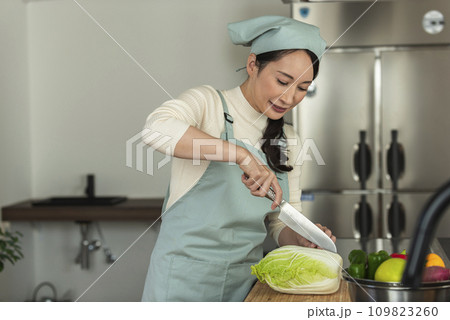 包丁で白菜を切るエプロン姿の女性 109823260