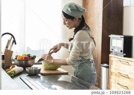 包丁で白菜を切るエプロン姿の女性 109823266