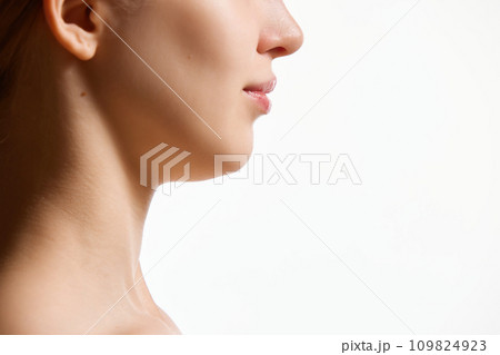 Cropped side view image of female face, neck isolated against white studio background. Reduction of double chin. 109824923