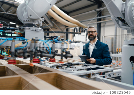 Male engineer in modern industrial factory, checking robotic arm, controling process and manufacturing equipment and machinery. Manufacturing facility with robotics and automation. Male engineer in modern industrial factory, checking robotic arm, controling process and manufacturing equipment and machinery. Manufacturing facility with robotics and automation. 109825049