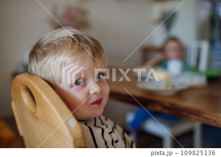 Little boy eating breakfast in high chair in home kitchen. Healthy breakfast or snack before day care. Little boy eating breakfast in high chair in home kitchen. Healthy breakfast or snack before day care. 109825136