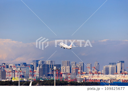 羽田空港を離陸する旅客機と羽田沖のビル群 109825677