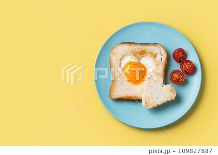 Valentine's Day breakfast with egg with tomatoes, heart shaped and toast bread on yellow background 109827887