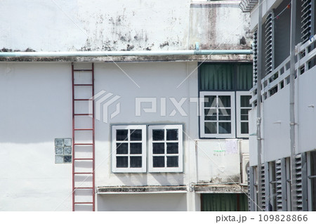 Window and white wall of building with steel ladder. Window and white wall of building with steel ladder. 109828866