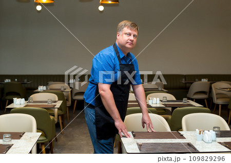 A man clears a table in a cafe at the end of the working day 109829296