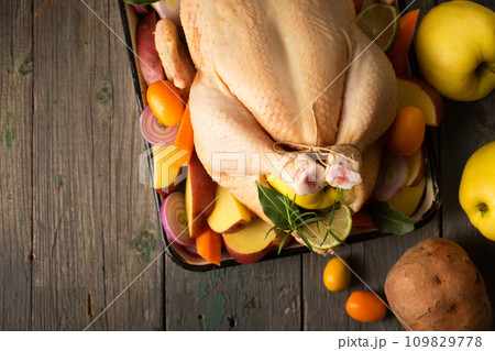 A large chicken stuffed with an apple with vegetables and fruits, top view A large chicken stuffed with an apple with vegetables and fruits, top view 109829778