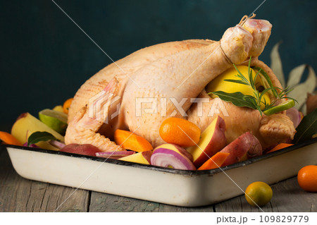 A large chicken stuffed with an apple with vegetables and citrus fruits A large chicken stuffed with an apple with vegetables and citrus fruits 109829779