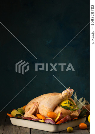 A large chicken stuffed with an apple with vegetables and citrus fruits, copy space 109829782